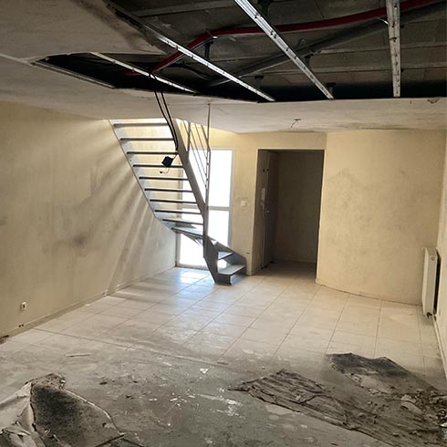 Intérieur de logement endommagé par un dégât des eaux, murs, sols et plafond abîmés.